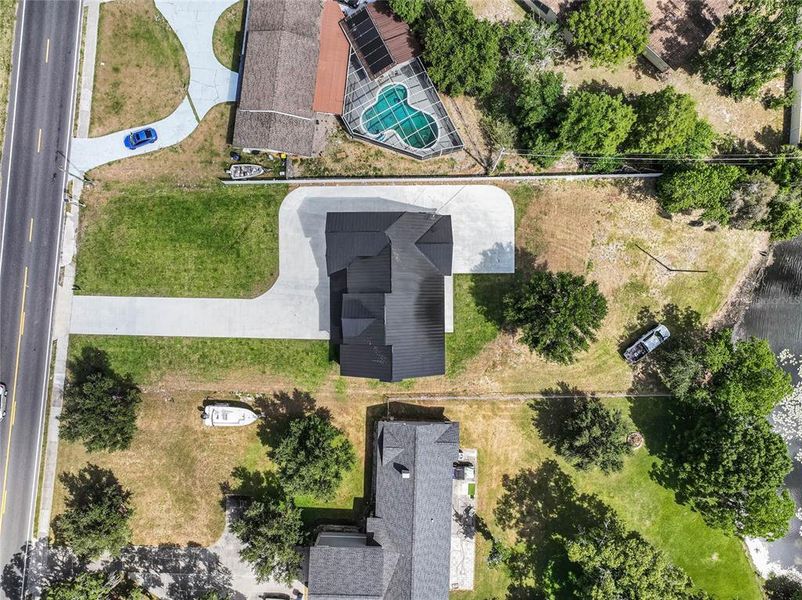 aerial view showcases a unique, modern home distinguished by its bold, angular architecture and striking dark exterior. Situated on a generous plot, this property offers ample outdoor space, ideal for landscaping or potentially adding recreational features like a garden or patio.