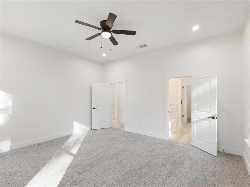 Unfurnished bedroom with light colored carpet, a ceiling fan, ensuite bath, and recessed lighting