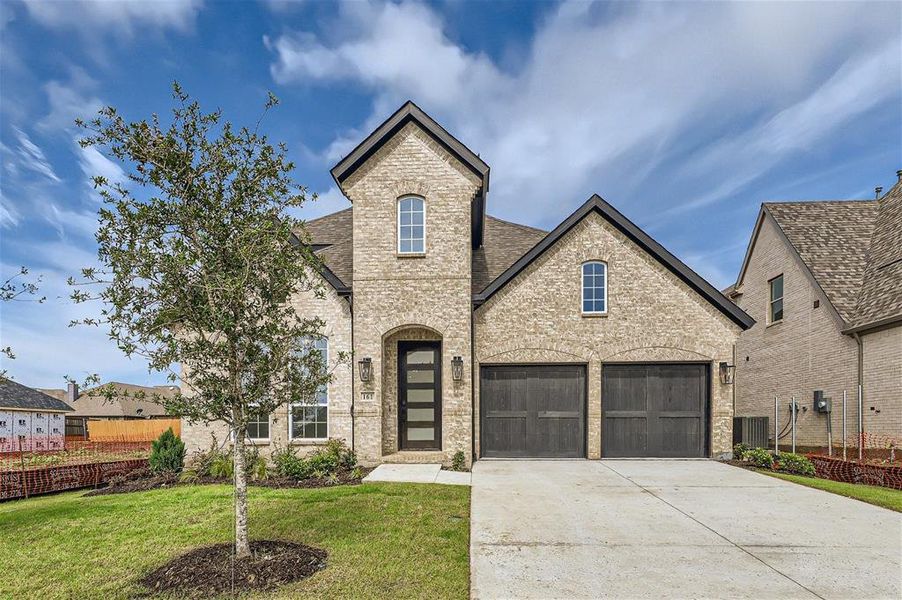 French provincial home featuring a front lawn and a garage