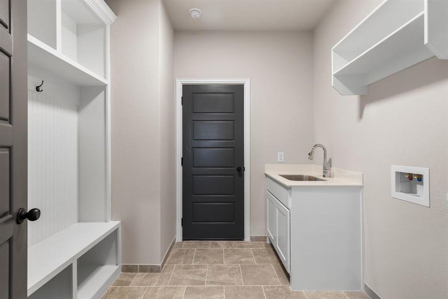 Laundry area featuring sink, washer hookup, cabinets, and light tile patterned floors