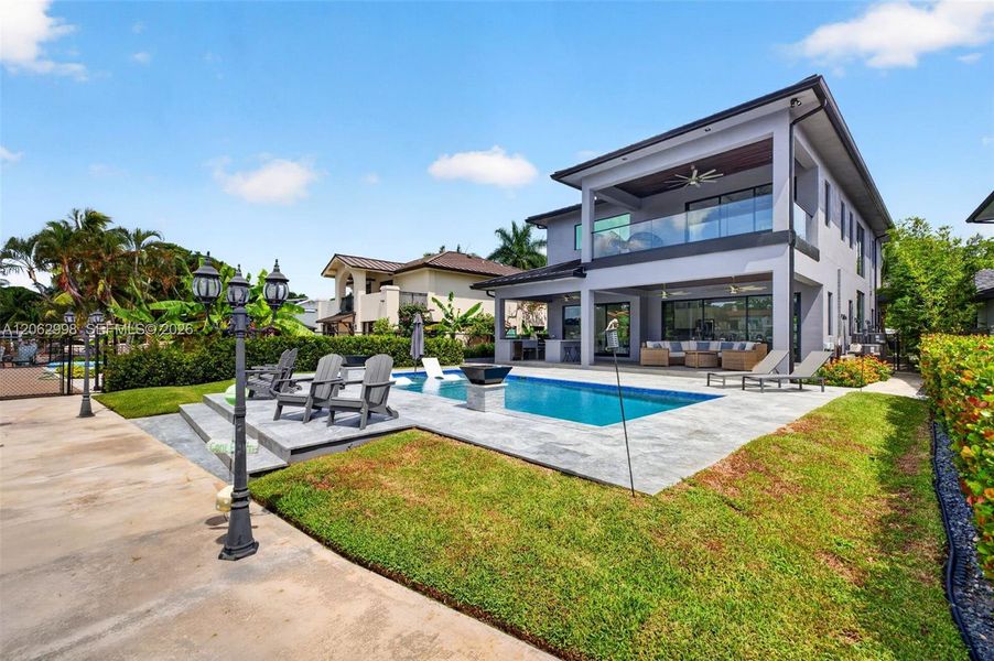 View from the new concrete dock and seawall to the Salt chlorinated pool w/ water features, LED color changing light, sun shelf with umbrella hole and in water stools. Stone decking surrounds the pool