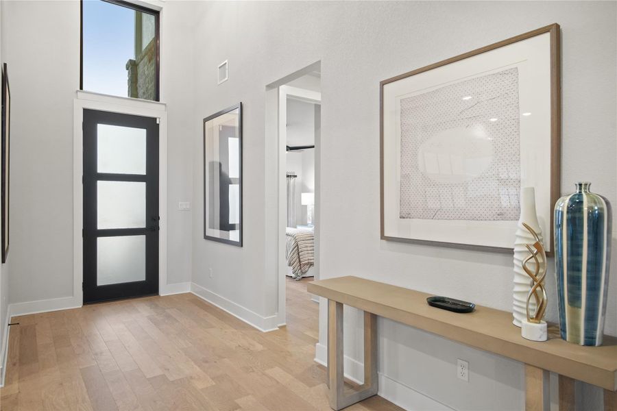 Foyer entrance featuring light wood-style flooring and a towering ceiling