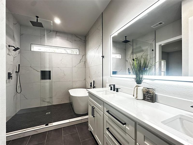 Bathroom with a marble finish shower, double vanity, a soaking tub, and dark tile patterned flooring Bathroom with a marble finish shower, double vanity, a soaking tub, and dark tile patterned flooring