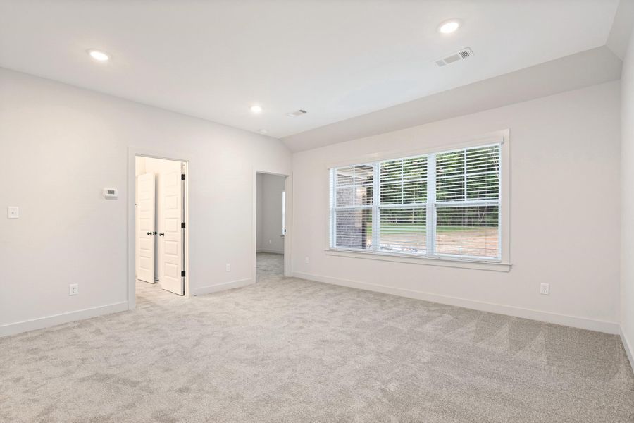 Spacious room featuring light-colored carpet flooring, recessed lighting, and a large window with white blinds Spacious room featuring light-colored carpet flooring, recessed lighting, and a large window with white blinds