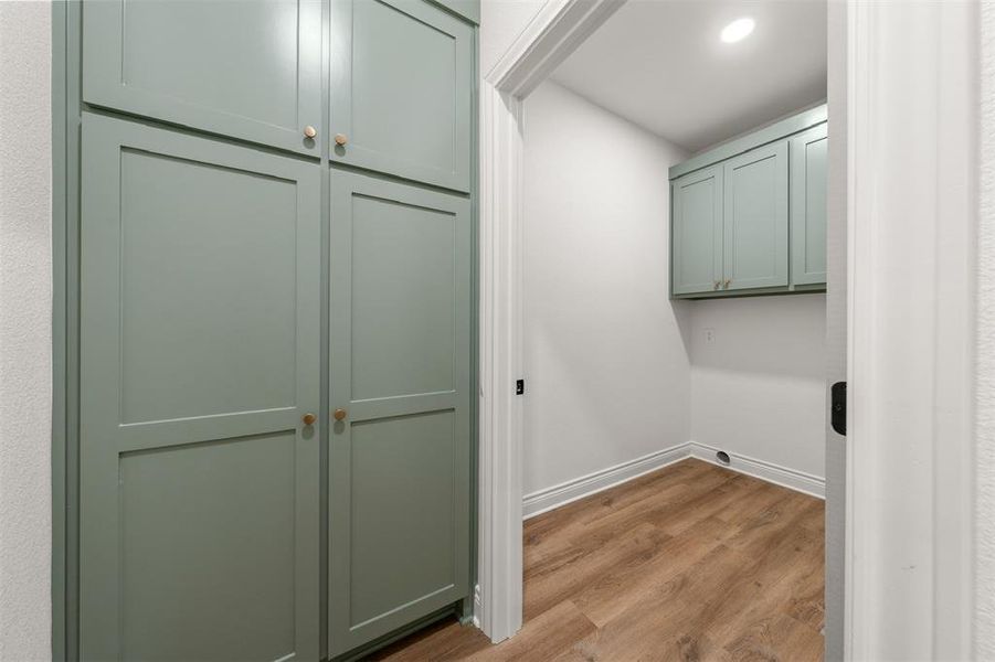 Laundry room with light wood finished floors, cabinet space, and recessed lighting Laundry room with light wood finished floors, cabinet space, and recessed lighting