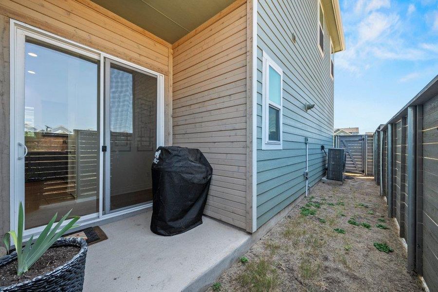 Sliding glass doors open onto a private concrete patio flanked by a fenced side yard. Sliding glass doors open onto a private concrete patio flanked by a fenced side yard.