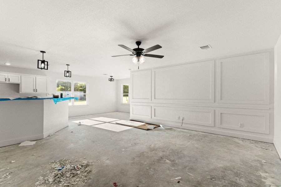 Unfurnished living room featuring a ceiling fan and concrete flooring Unfurnished living room featuring a ceiling fan and concrete flooring