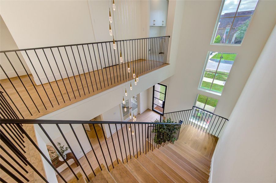 A striking architectural centerpiece, the dramatic staircase is complemented by soaring two-story ceilings, a cascading designer chandelier, and expansive windows that flood the home with natural light. The open railing design enhances the sense of scale and sophistication, creating a breathtaking first impression that sets the tone for the exceptional craftsmanship found throughout the residence.