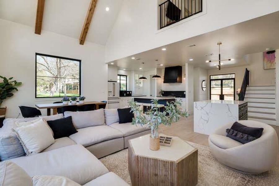 Living area with high vaulted ceiling, recessed lighting, beam ceiling, and stairs