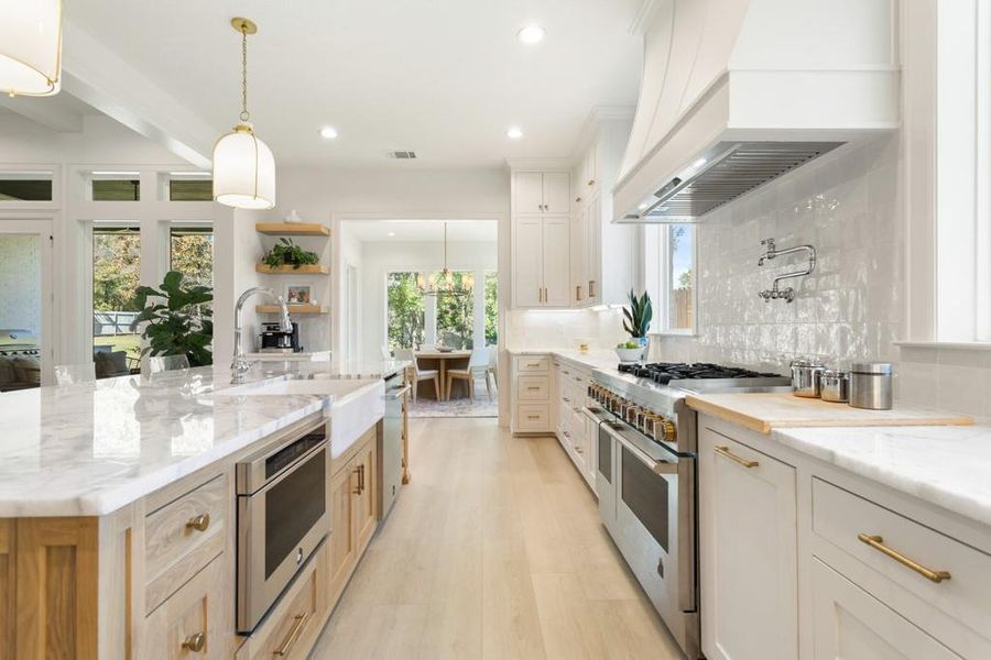 Kitchen with decorative light fixtures, stainless steel appliances, decorative backsplash, light stone counters, and recessed lighting