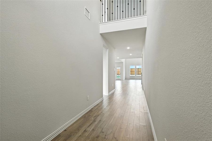 Hall with a textured wall and hardwood / wood-style floors