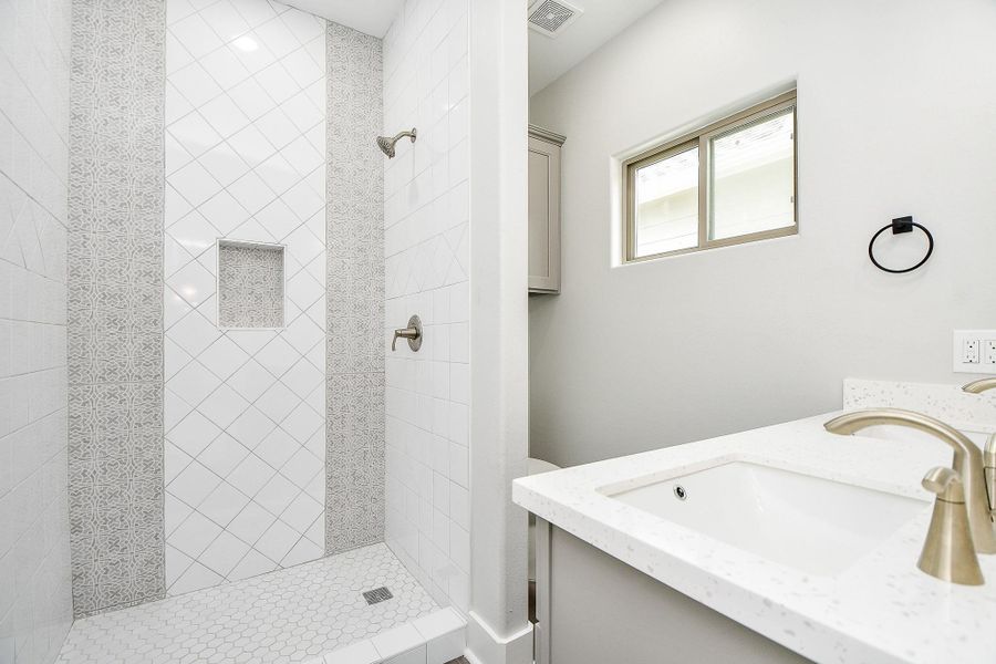 This is a modern Master bathroom featuring a walk-in shower with decorative tile work, a single vanity with ample counter space, and a sleek design. This is a modern Master bathroom featuring a walk-in shower with decorative tile work, a single vanity with ample counter space, and a sleek design.