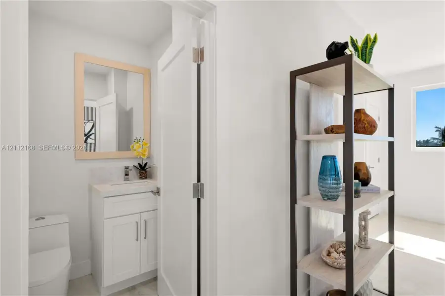 White cabinetry with stone-surfaced countertop, integrated under-mount sink, polished chrome faucet, and rectangular mirror with light wood-finish frame White cabinetry with stone-surfaced countertop, integrated under-mount sink, polished chrome faucet, and rectangular mirror with light wood-finish frame
