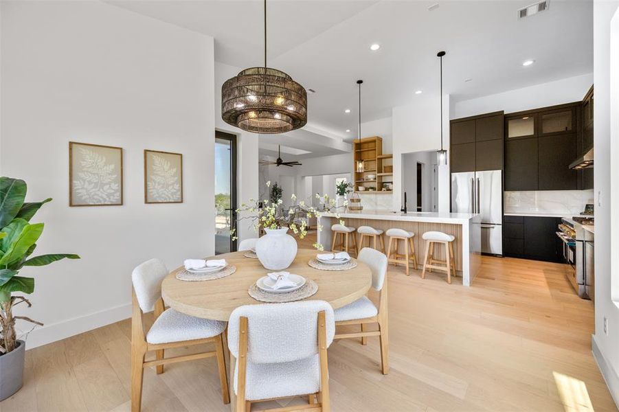 Blonde wood flooring and an inviting dining area flow seamlessly into a modern kitchen.