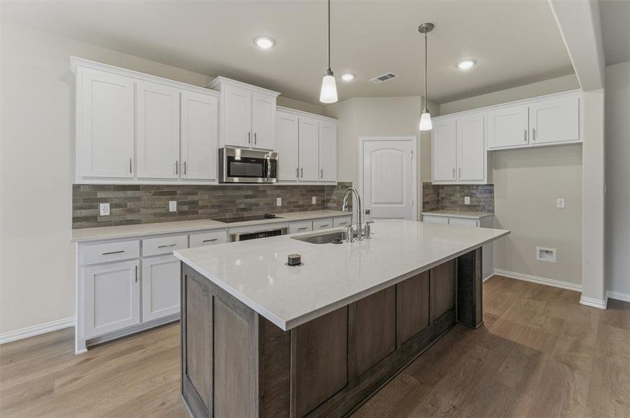 Open-concept kitchen featuring an expansive center island with a white countertop and seating overhang