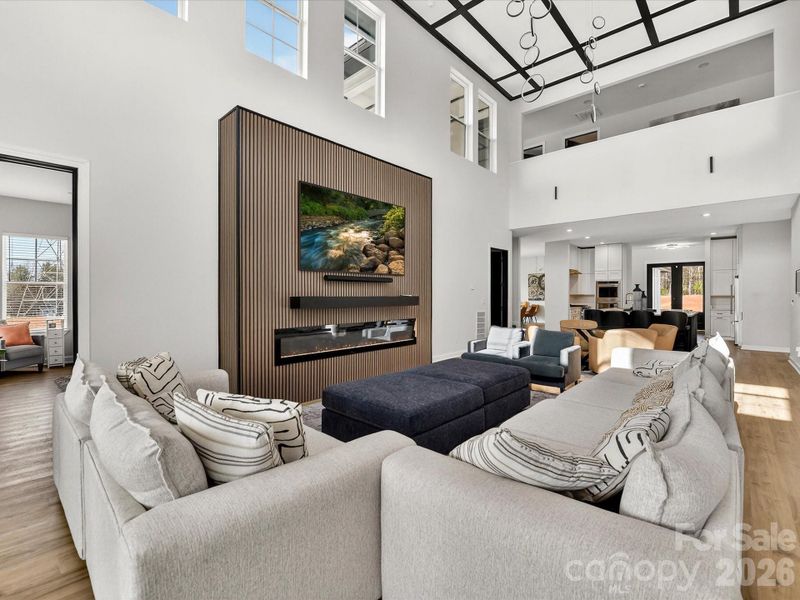 Bright, open-concept family room with soaring ceilings, a statement fireplace wall, and seamless flow into the kitchen and dining areas.