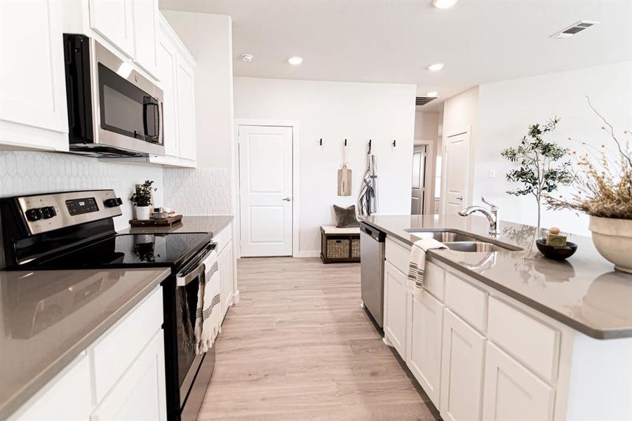 Kitchen featuring stainless steel appliances, white cabinets, light wood-type flooring, recessed lighting, and decorative backsplash Kitchen featuring stainless steel appliances, white cabinets, light wood-type flooring, recessed lighting, and decorative backsplash
