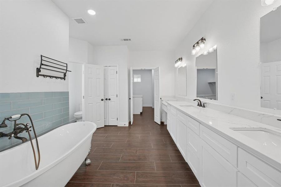 Bathroom featuring a freestanding tub, double vanity, wood tiled floors, a closet, and tile walls