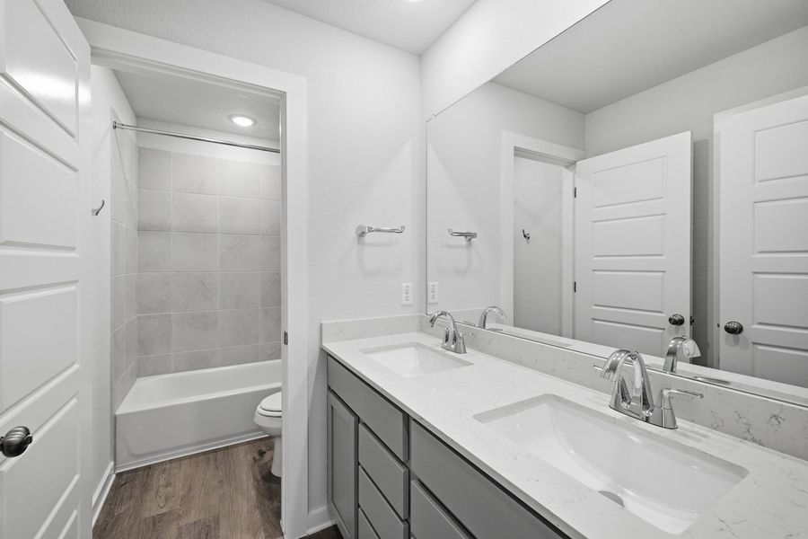 A well-appointed bathroom offers a double vanity with ample counter space and a clean shower-tub combination.