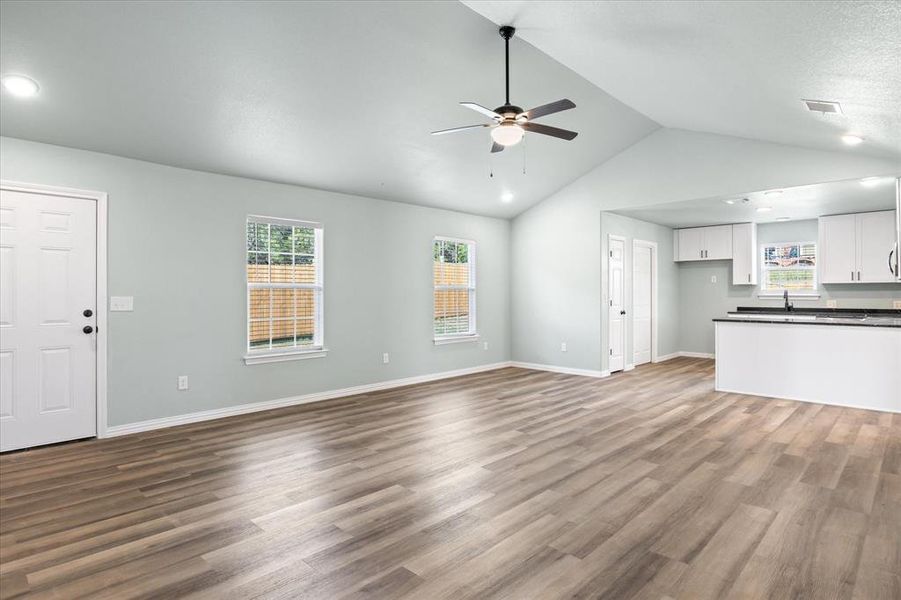 Unfurnished living room featuring vaulted ceiling, ceiling fan, and hardwood / wood-style flooring