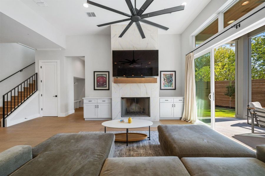 Living room with a high end fireplace, wood finished floors, stairway, and recessed lighting