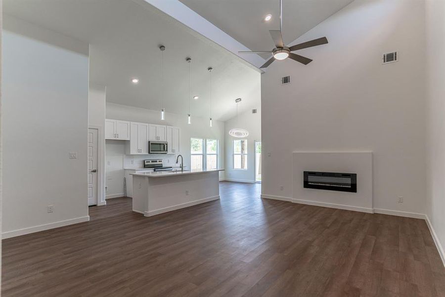 Open concept layout of living room looking into kitchen and dining area