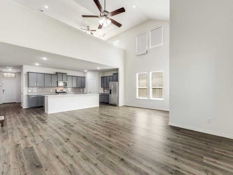 Unfurnished living room with a ceiling fan, high vaulted ceiling, dark wood finished floors, and recessed lighting