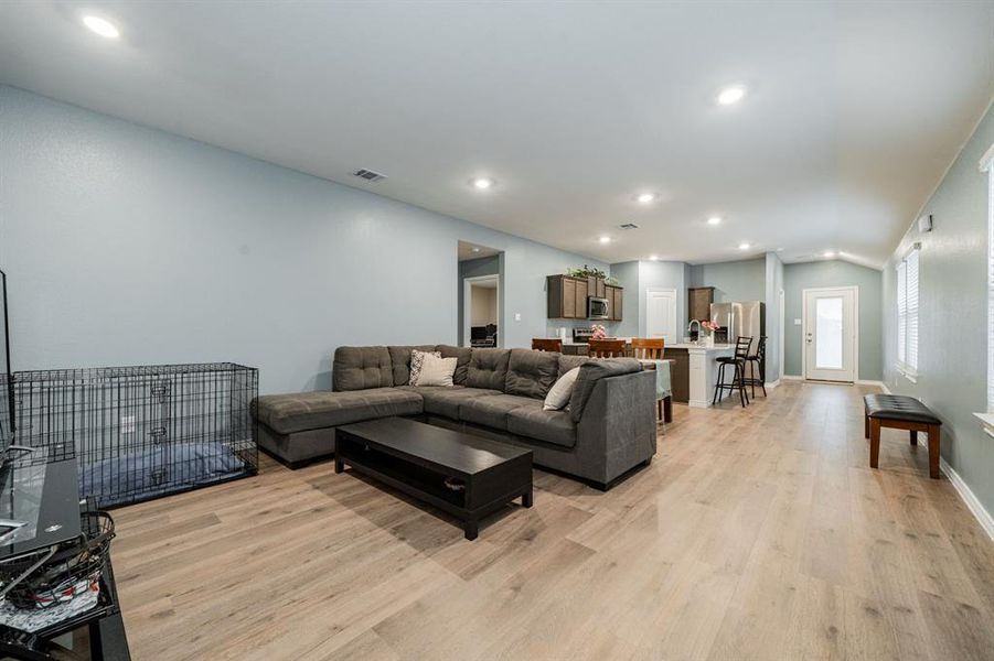 Living room with light wood finished floors, recessed lighting, and vaulted ceiling Living room with light wood finished floors, recessed lighting, and vaulted ceiling