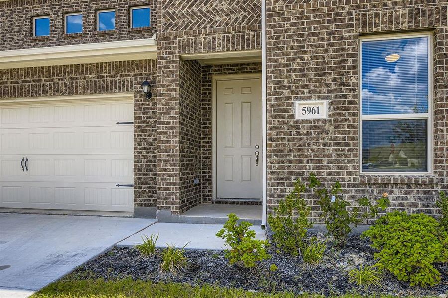View of exterior entry with brick siding, concrete driveway, and a garage View of exterior entry with brick siding, concrete driveway, and a garage