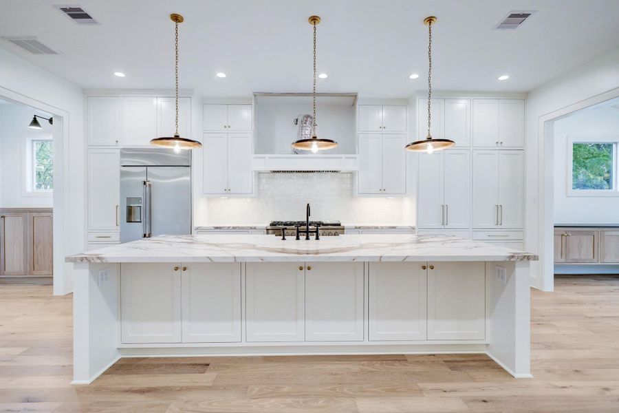 The kitchen boasts desirable amenities with floor to ceiling cabinetry & storage, white subway tile backsplash, sleek stainless appliances and a large island with additional storage and seating. *Previous Project*