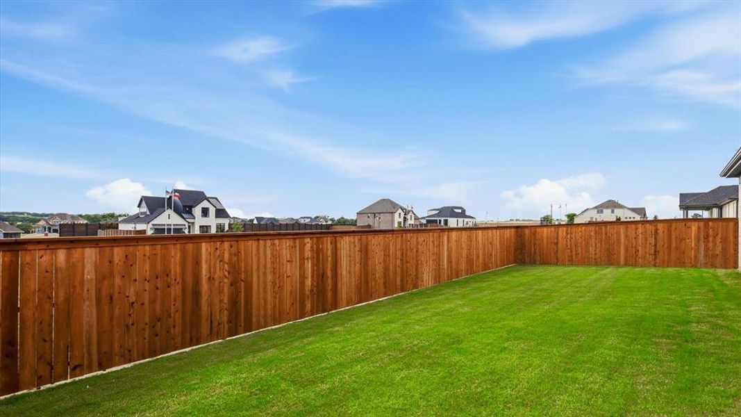 Expansive backyard featuring a manicured lawn, full privacy fencing, and ample space for outdoor activities
