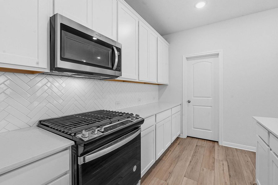 A well-equipped kitchen showcases pristine white cabinetry and a modern gas range. A well-equipped kitchen showcases pristine white cabinetry and a modern gas range.