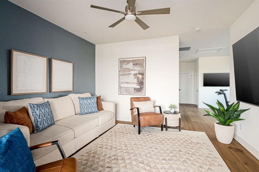 Living area with wood finished floors, ceiling fan, and attic access