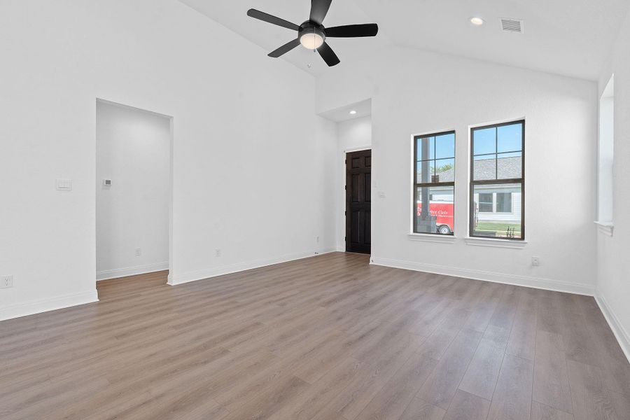 Spare room with light wood finished floors, high vaulted ceiling, a ceiling fan, and recessed lighting Spare room with light wood finished floors, high vaulted ceiling, a ceiling fan, and recessed lighting