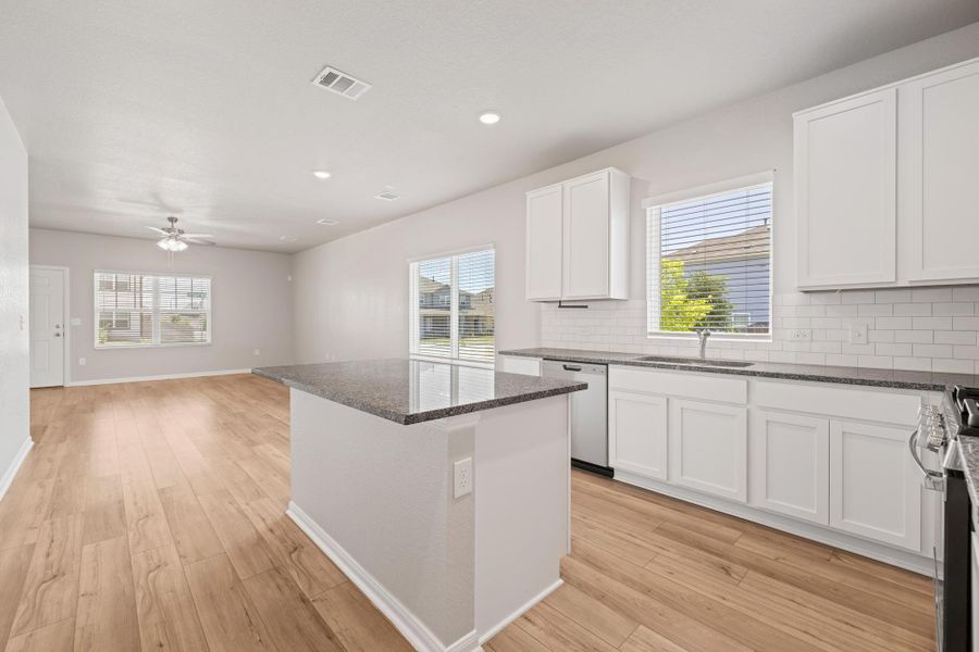 Kitchen with decorative backsplash, stainless steel range oven, light wood-style flooring, a center island, and recessed lighting Kitchen with decorative backsplash, stainless steel range oven, light wood-style flooring, a center island, and recessed lighting