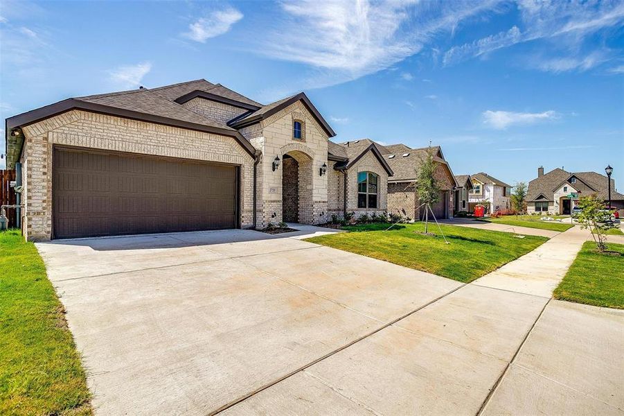 French country inspired facade featuring a garage and a front lawn