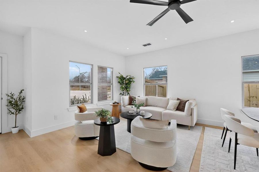 Living area with a ceiling fan, light wood-style flooring, and recessed lighting