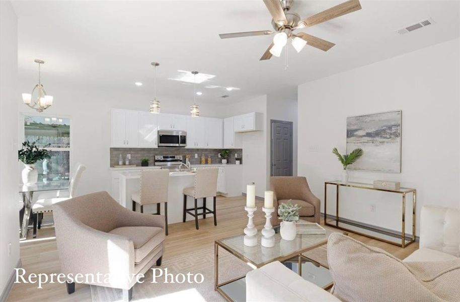 Living room with light hardwood / wood-style flooring and ceiling fan with notable chandelier