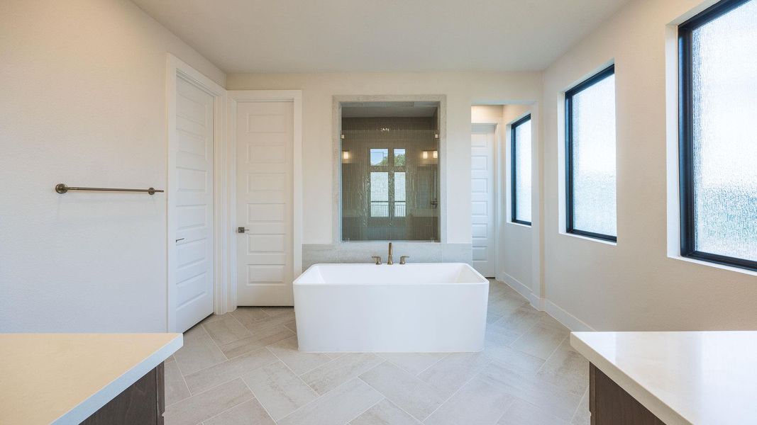 Bathroom featuring a freestanding bath, vanity, and light tile patterned floors Bathroom featuring a freestanding bath, vanity, and light tile patterned floors