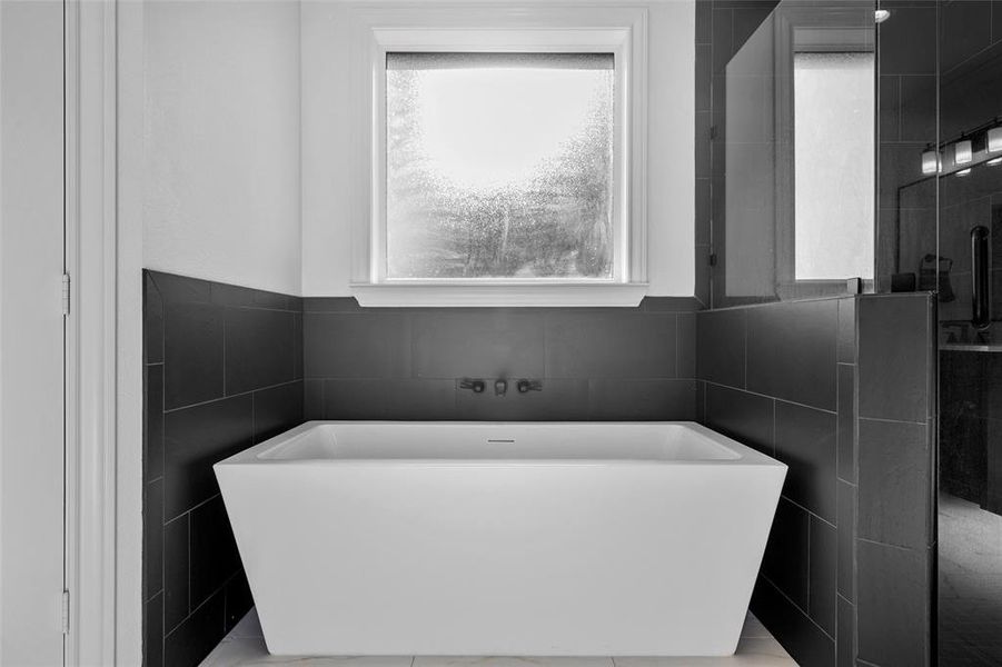 Bathroom featuring healthy amount of natural light, tile walls, a freestanding bath, and tiled shower Bathroom featuring healthy amount of natural light, tile walls, a freestanding bath, and tiled shower