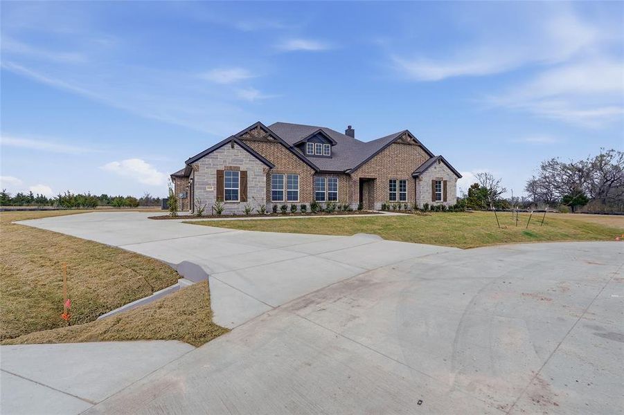 View of front of house with concrete driveway, a front lawn, stone siding, and a chimney