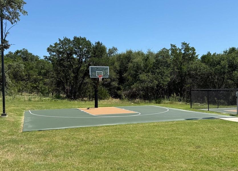 An outdoor basketball court beckons for active recreation amidst natural surroundings. An outdoor basketball court beckons for active recreation amidst natural surroundings.
