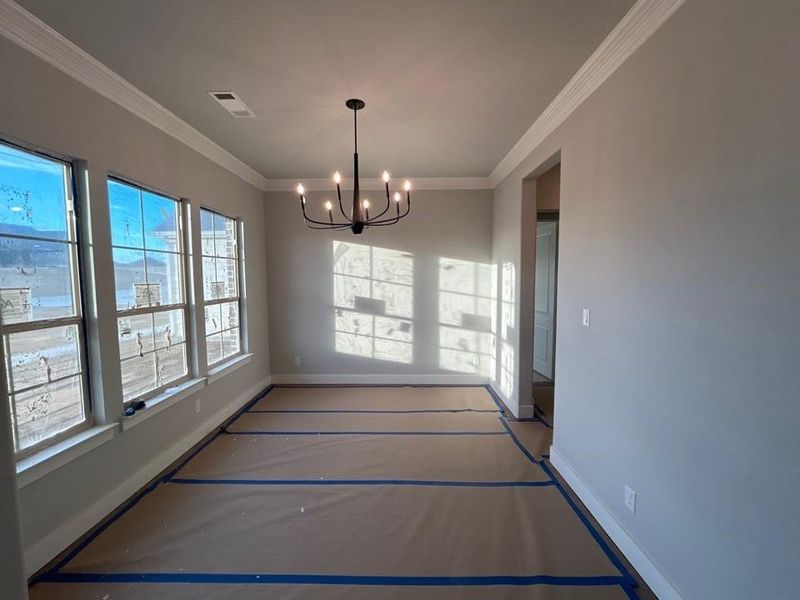 Unfurnished dining area with a chandelier and crown molding