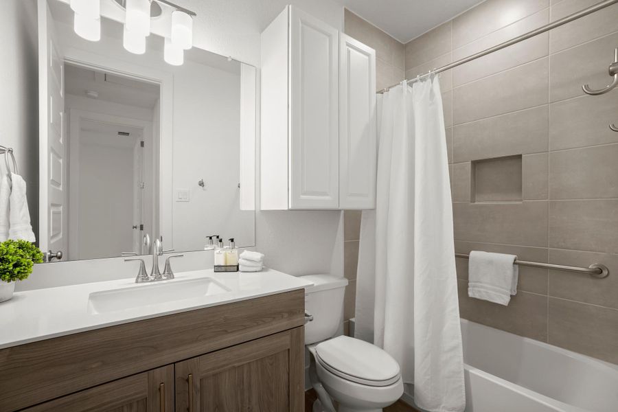 A well-appointed bathroom features a sleek vanity, modern fixtures, and tiled shower surround.