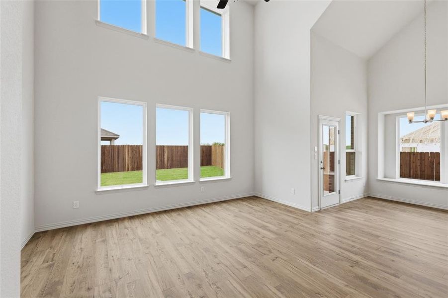 Double-height living area featuring wood-finish flooring, a wall of windows, and an upper transom window bank
