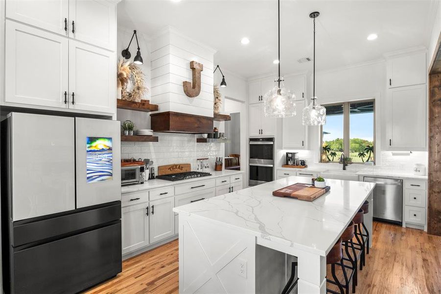 Kitchen featuring appliances with stainless steel finishes, open shelves, white cabinets, recessed lighting, eat at island