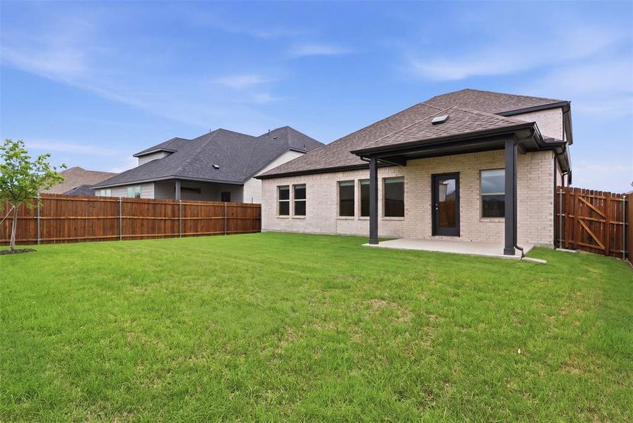 The property features a spacious backyard with a large grassy lawn and a wooden privacy fence