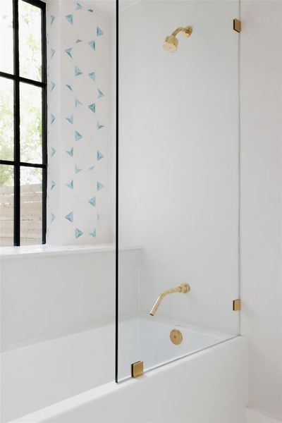The guest bath exudes modern elegance with its sleek glass shower enclosure and striking geometric tile, offering a sophisticated and stylish touch.