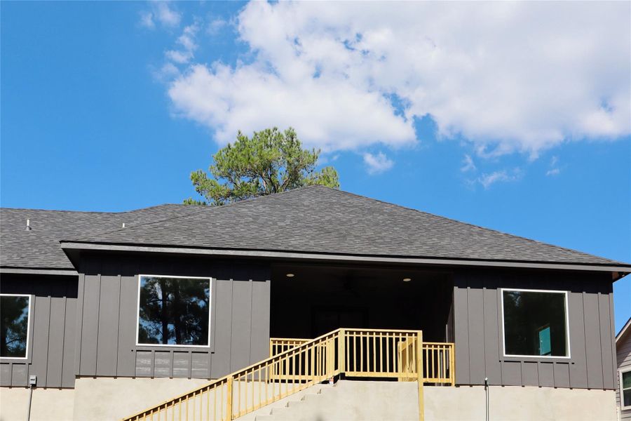 Rear view of house featuring a shingled roof, stairway, and board and batten siding