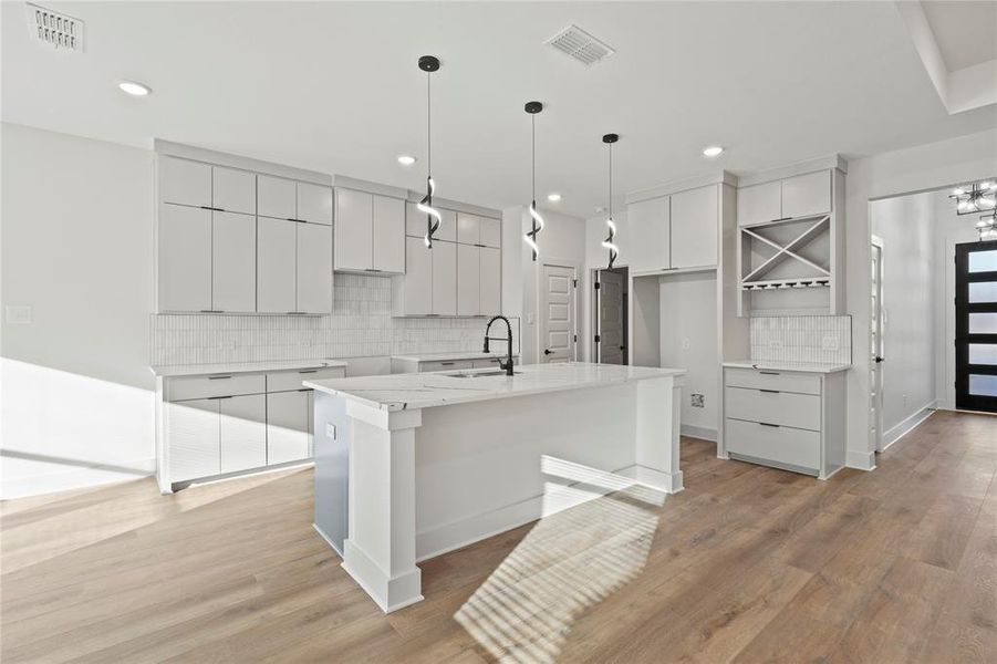 Kitchen featuring a kitchen island with sink, visible vents, a sink, and modern cabinets